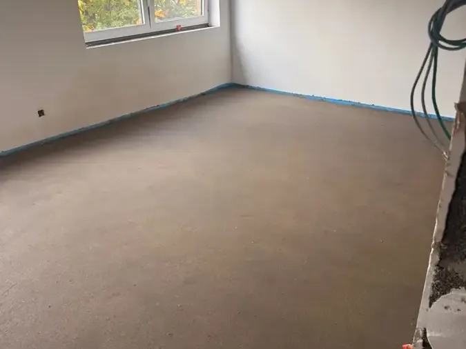Chape lissée dans une pièce vide, bande périphérique bleue le long des murs