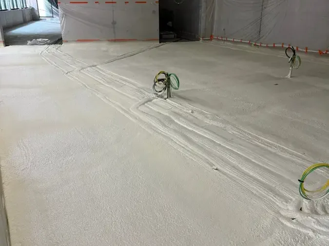 Sol d'un grand plateau recouvert de mousse polyuréthane projetée par M.I.C Thermique, murs protégés par bâches et scotch orange