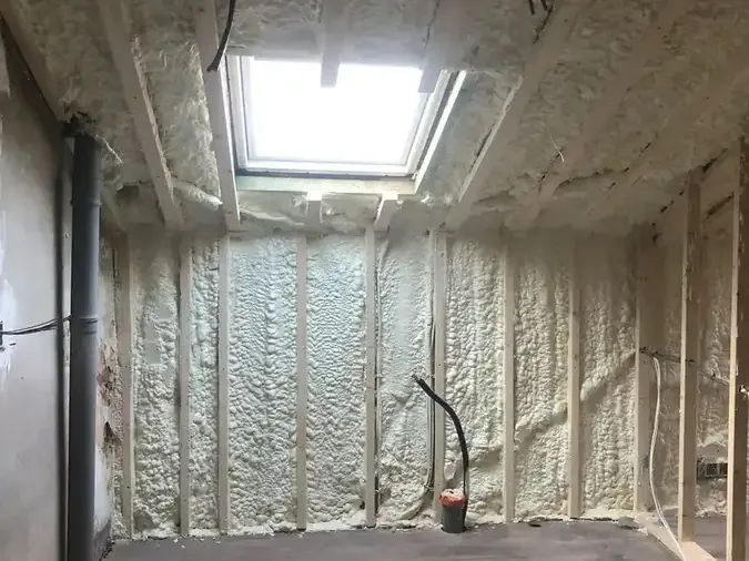 Pièce mansardée isolée à la mousse polyuréthane projetée entre les chevrons, sous une fenêtre de toit