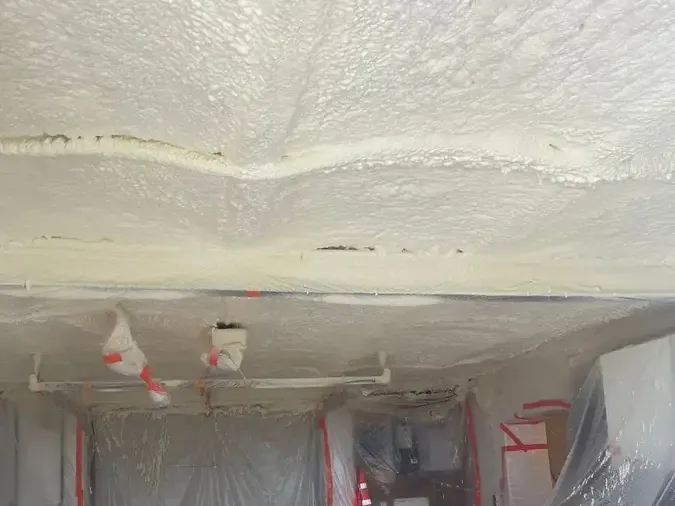 Plafond de garage isolé à la mousse polyuréthane projetée par M.I.C Thermique, porte et murs protégés par des bâches