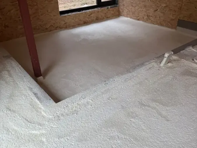 Sol isolé à la mousse polyuréthane projetée en continu jusque contre les murs, dans une pièce à murs OSB
