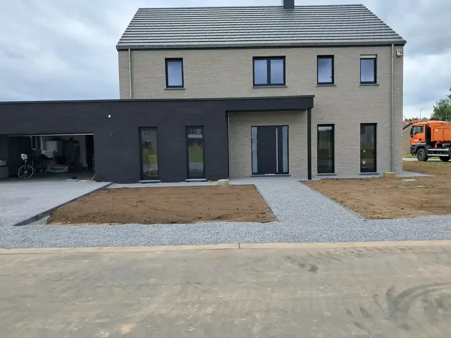 Façade d'une maison neuve en briques claires et noires, abords en gravillons
