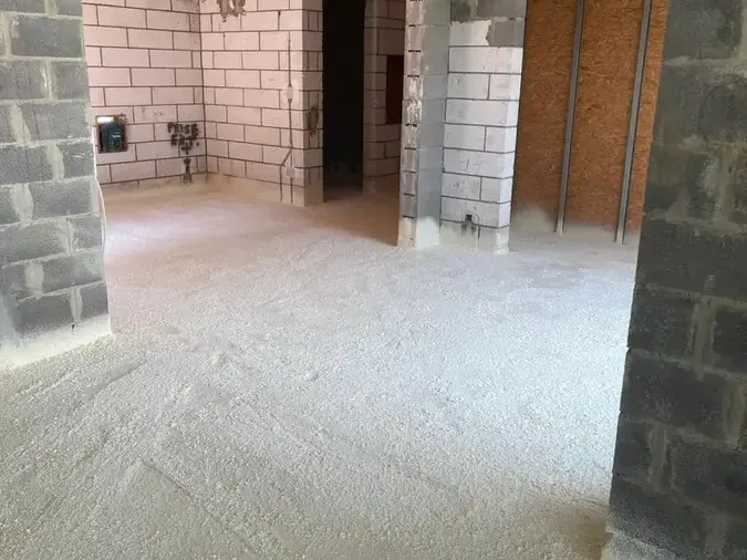 Vaste pièce brute en blocs de béton, sol isolé à la mousse polyuréthane projetée