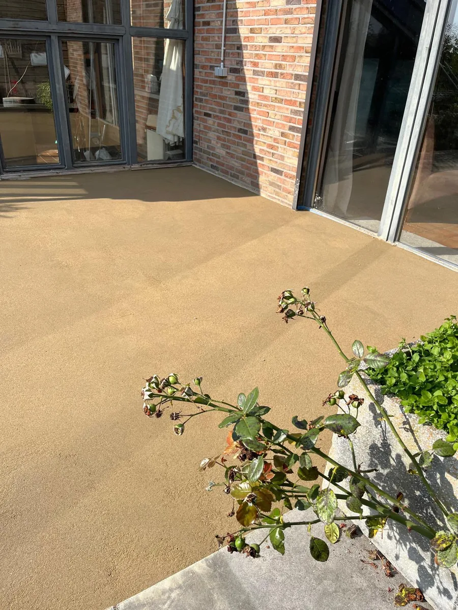 Tapis de pierre beige posé sur une terrasse devant de grandes baies vitrées