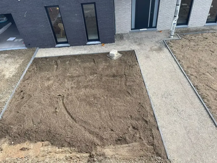 Terre nivelée encadrée de bordures et d'allées en gravillons devant une maison neuve